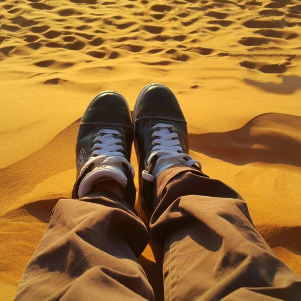 Enjoy a peaceful moment on sand dunes as the sun sets, casting a warm glow.