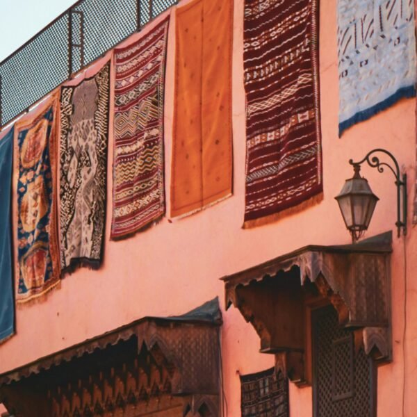 Vibrant Moroccan rugs displayed on a traditional building in Marrakesh, showcasing local craftsmanship.