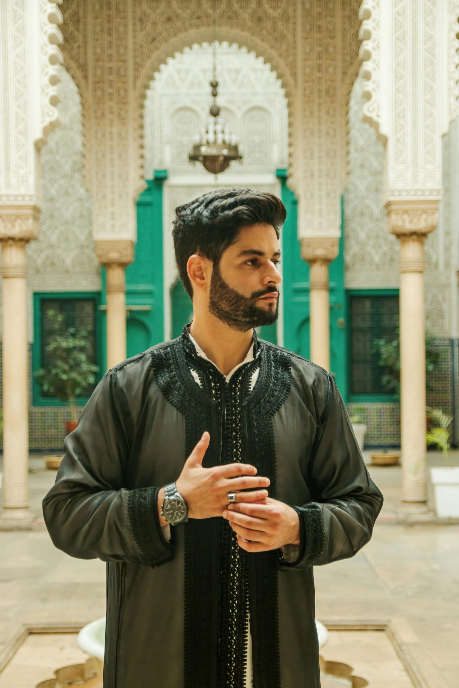 Portrait of a man in traditional Moroccan attire inside a stunning architectural landmark. Perfect for cultural themes.