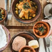 Delicious Moroccan dishes served with fresh vegetables and traditional bread on a woven mat.