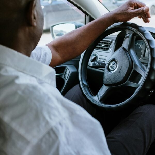 A man driving a vehicle, highlighting the steering wheel and car interior.